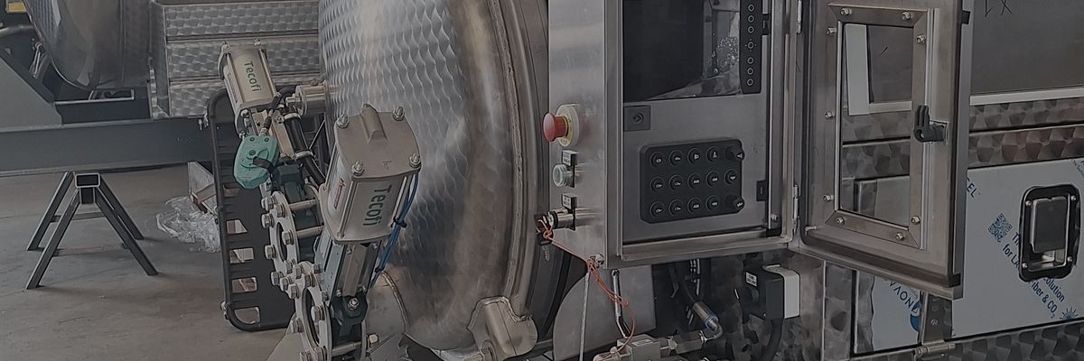 Stainless steel panel open on the side of a vacuum truck during testing in the workshop.